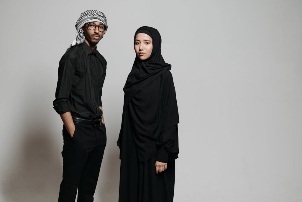 Elegant portrait of a man and woman in traditional Middle Eastern attire on a neutral background.