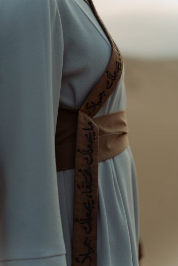 Close-up view of a woman wearing an elegant dress with Arabic calligraphy embroidery.